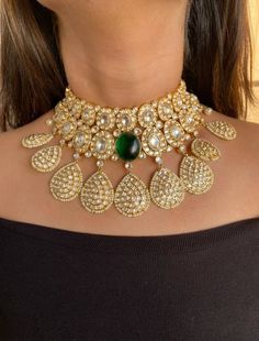 This green choker features a beautiful design that is aesthetically pleasing and aptly contemporary. The choker worked in gold plated silver alloy, is finished off with A center Hydro/Lab Emerald Stone and beautiful Fine setting of Uncut polki look Kundan . With Beautiful Work Of Kundan drop Hangings. Necklace Closure - Adjustable Dori Earrings Closure - Push Back Style Tip - Being a strong supporter of the intersection of classic and contemporary, we love designs that are contemporary yet boast Diwali Designer Tilla Necklace, Designer Gold Necklaces For Festivals, Bollywood Style Cutdana Necklace For Designer Wear, Designer Tilla Necklaces, Kundan Tilla Choker Necklace For Reception, Designer Gold Necklace For Festive Occasions, Designer Wedding Necklaces For Festive Occasions, Designer Festive Wedding Necklaces, Designer Gold Kundan Necklace