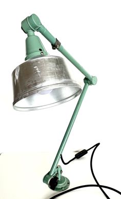 a green table lamp sitting on top of a white counter next to a black cord