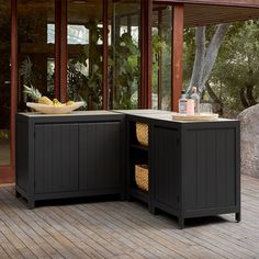 an outdoor kitchen with two black cabinets on the deck and a bowl of fruit in the center