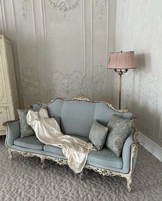 a blue couch sitting in front of a white dresser next to a light colored lamp