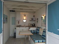 an open door leading to a kitchen and living room area with blue walls, white cabinets and wood flooring