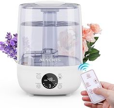 a person holding a remote control in front of a small machine with flowers on it