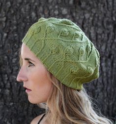 a woman wearing a green knitted hat next to a tree