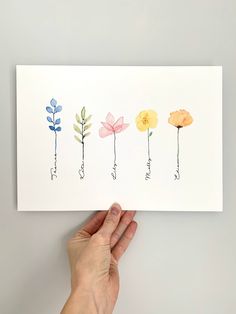 a hand holding up a card with five flowers on it, all in different colors