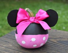 a minnie mouse ornament with a pink bow sitting on top of a wooden table