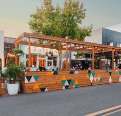 an outdoor bar with colorful geometric designs on the wall and potted plants in front