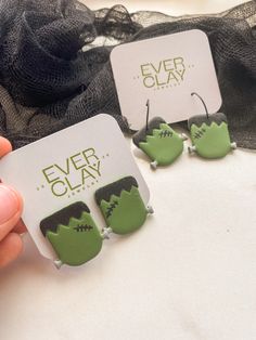 there are two green monster earrings on the table