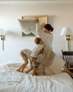 a woman and child are playing on the bed