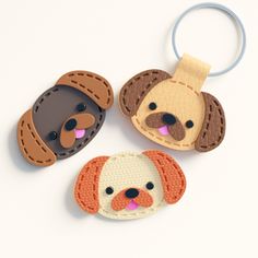 three dog shaped key chains on a white surface, one is brown and the other is black