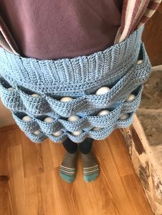 a person standing in front of a wooden floor wearing socks and a blue crocheted skirt