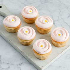 six cupcakes with pink frosting on a tray