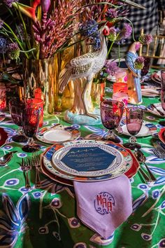 the table is set with colorful flowers and place settings