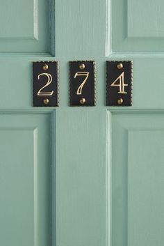 the door is painted green and has two black numbers on it with gold studs