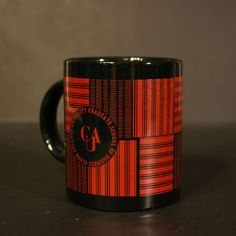 a red and black coffee mug sitting on top of a table