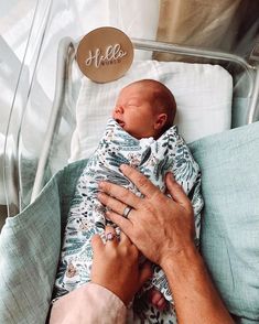 a person holding a baby in a hospital bed with the name hello written on it