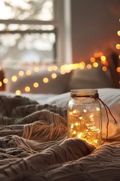 a jar filled with lights sitting on top of a bed