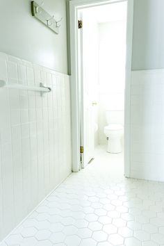 a bathroom with white tile and hexagonal tiles on the floor, along with an open door