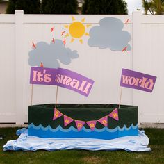 there is a sign that says it's small world in front of a white fence