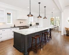 a large kitchen with an island in the middle and two bar stools at the end