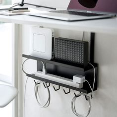 a laptop computer sitting on top of a desk next to a wall mounted charger