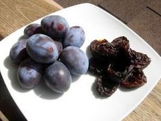 a white plate topped with plums and raisins on top of a wooden table