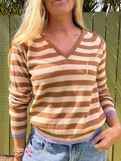 Stay stylish and cozy in our Emery striped sweater! This knitted top features a flattering V-neck, long sleeves, and a trendy striped pattern. Perfect for staying warm and looking chic. Why we love it: This sweater is nice and light weight with slight v neck that's not too low. The pop of purple on the cuff and hem is really fun and adds just little something special to this otherwise neutral stripe. Great for layering when traveling or throwing in your bag if you're worried about maybe getting Striped V-neck Winter Sweater, Striped V-neck Sweater For Winter, Winter Striped V-neck Sweater With Long Sleeves, Winter Striped V-neck Long Sleeve Sweater, Winter Striped Long Sleeve V-neck Sweater, Striped Long Sleeve V-neck Sweater For Winter, Casual Striped V-neck Sweater With Long Sleeves, Casual Striped Long Sleeve V-neck Sweater, Striped V-neck Sweater For Fall