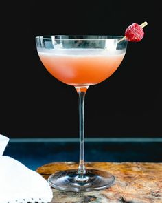 a pink cocktail with a raspberry garnish on the rim