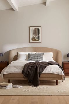 a bedroom with a bed, nightstands and pictures on the wall above it is shown