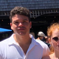 a man and woman standing next to each other in front of a building with blue umbrellas