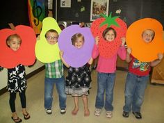 four children holding up paper cutouts in the shape of letters with fruit on them