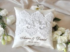 a wedding ring pillow and flowers on a white bed with the name adama and daniel written on it