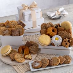 several different types of cookies and pastries in boxes on a table with silverware