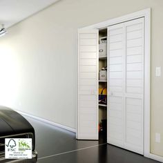 an empty room with white doors and black leather luggage in front of the open door