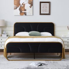 the bed is made up with black velvet and gold trimmings, along with two pictures on the wall