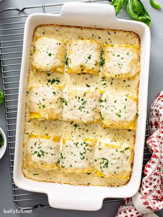 a casserole dish with cheese and herbs on top, sitting on a cooling rack