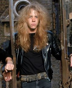 a man with long hair standing in front of a door