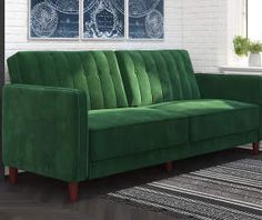 a green couch sitting in front of a white brick wall