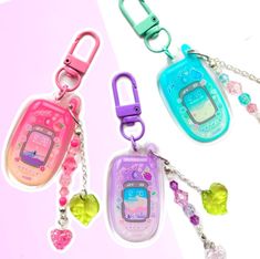 three different cell phones are hanging from key chains