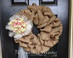 a burlock wreath is hanging on the front door with flowers and tulle