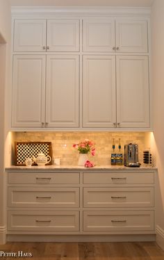 a kitchen with all white cabinets and counter tops in the corner, along with a coffee maker