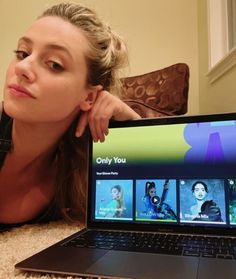 a woman laying on the floor in front of a laptop computer with an ad for spotify partner