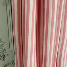 a pink and white striped curtain hanging on the side of a door with an ornate frame