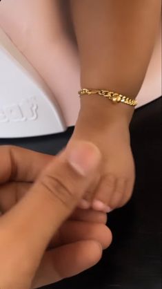 a woman is holding the hand of a man who is wearing a gold chain bracelet