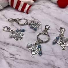 three charms with snowflakes on them sitting next to a stuffed animal and other items