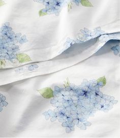 blue flowers on white sheets with green leaves