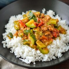 a black plate topped with rice and vegetables