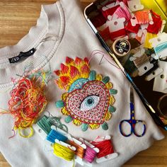 an embroidered t - shirt with scissors, thread and other crafting supplies on it