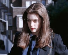 a woman with long brown hair wearing a suit and holding a purse in her hand