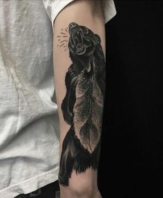 a man's arm with a black and white tattoo of a bear on it