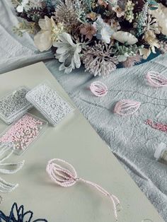 some pink and white beads are laying on a table next to a vase with flowers